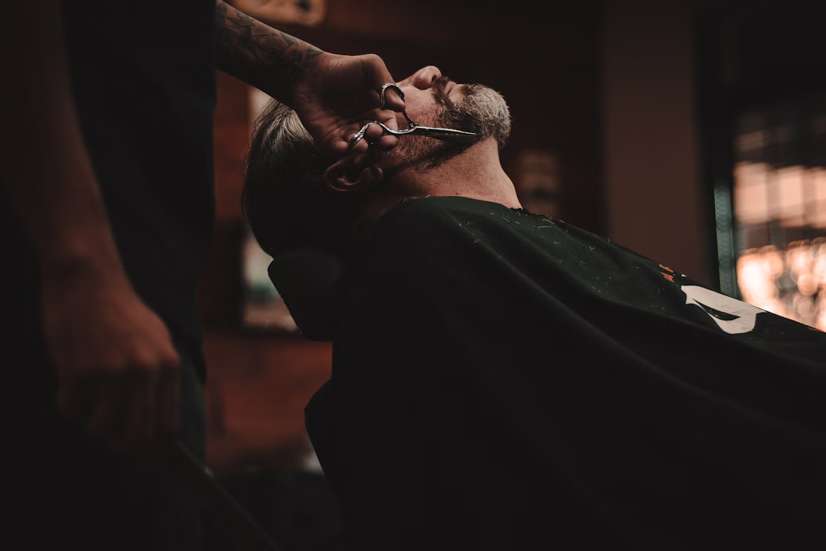 Barbeiro finalizando um corte masculino com técnica precisa.