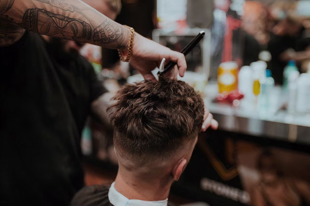 Cliente em uma cadeira de barbearia premium durante atendimento.